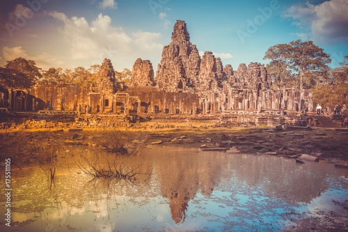 Angkor Wat Temple in Cambodia reflected in lake. Largest religious monument complex in the world. Ancient Khmer architecture. Orange ancient ruins against blue sky. Retro vintage toning