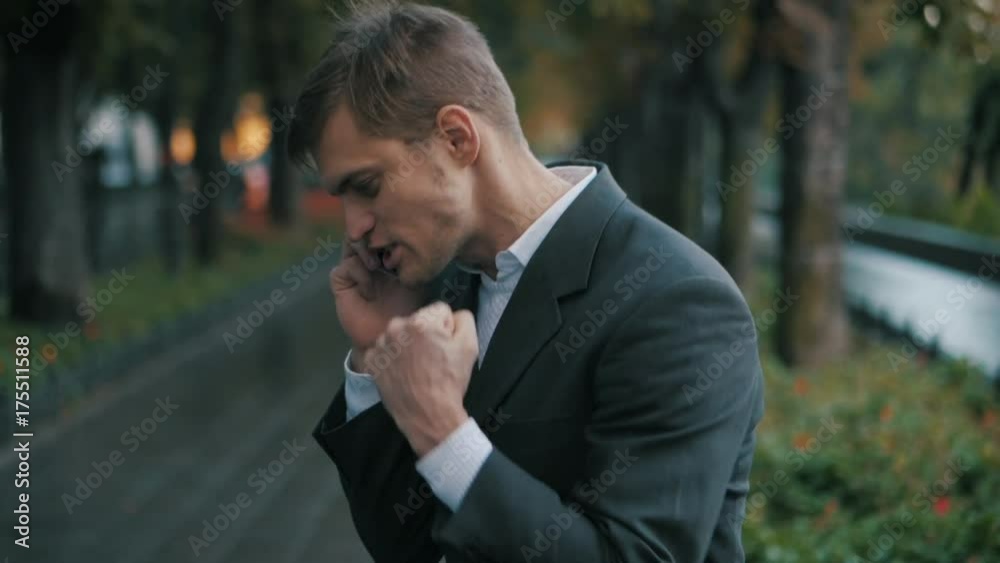 Young handsome businessman talking on mobile phone in the city. Guy heard good news and he is happy. Success concept. The joy of speaking on the phone. Slow motion. Young handsome businessman talking on mobile phone in the city. Guy heard good news and he is happy. Success concept. The joy of speaking on the phone. Slow motion.