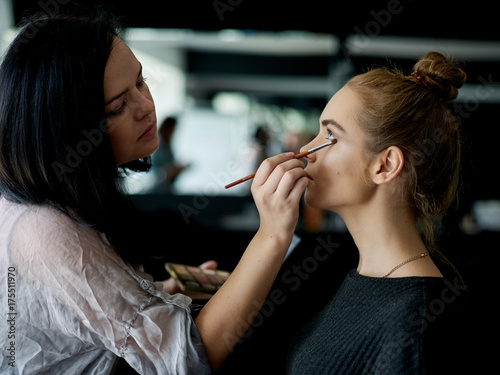 Make up artist doing professional make up of young woman. 