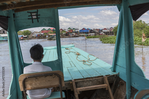 Rear view of man sitting on tourboat in Tonle Sap lake, Kampong Phluk, Siem Reap, Cambodia photo