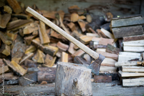 An axe stuck in piece of wood, ready for cutting a log / timber, pile of wood on a background