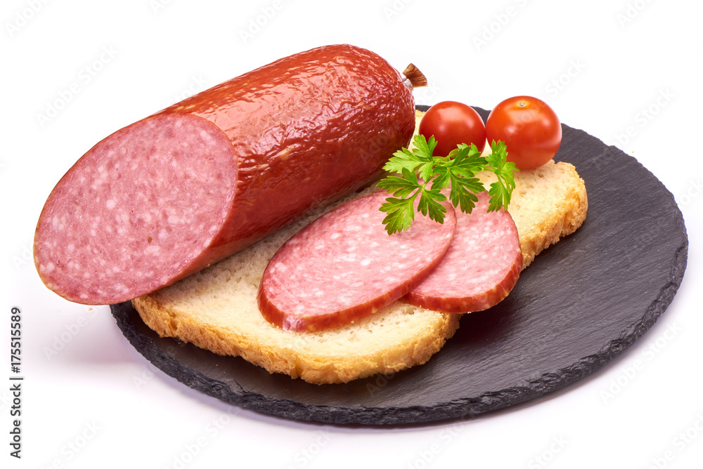 Salami sausages sliced with pepper, garlic and rosemary on cutting board on wooden table.