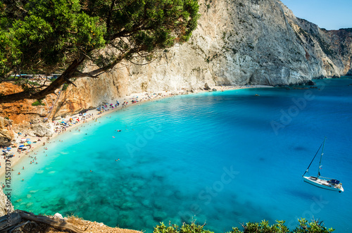 Porto Katsiki beach in Lefkada island, Greece. Beautiful view over the beach. The water is turquoise and there are tourists on the beach and a boat on the sea.