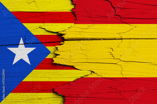 Catalonia independence movement versus Spain: symbolic for ongoing dispute on separation and autonomy. Flags of Catalan separatism and Spanish national flag painted on cracked wood background.