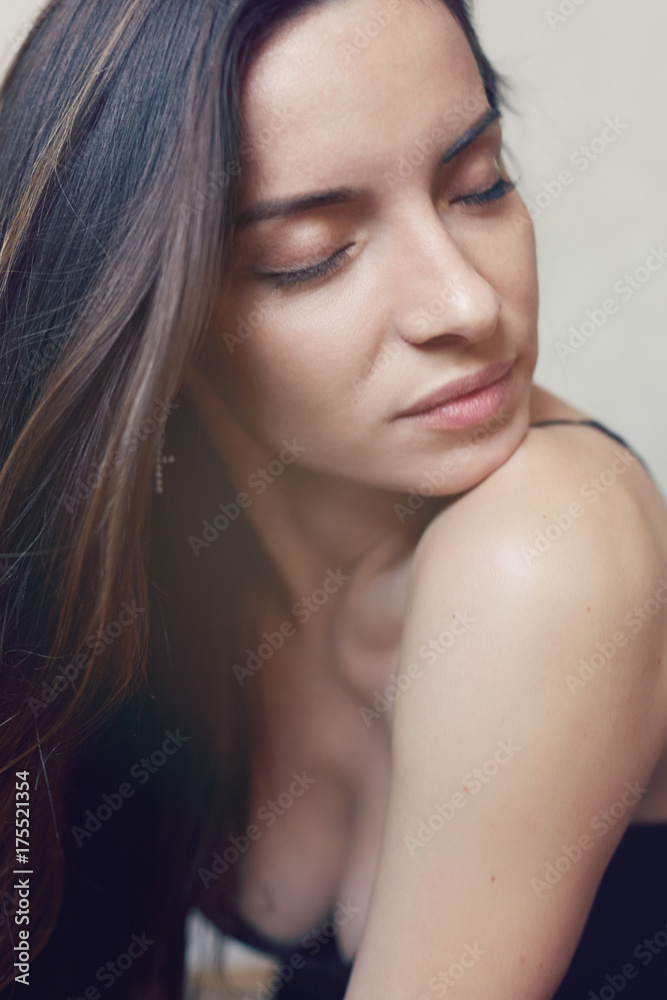 Close up highly-detailed picture of beautiful charming young female with perfect skin, brunette heavy long hair and closed eyes, resting indoors. Seductive lady posing in studio wall background.