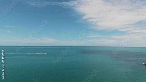 A boat or motor boat swiftly moves along the horizon along the water. The open sea, the blue sky. Water transport: movement on water. Sea, rest, boat. Drone view, birds eye angle. Yachting theme