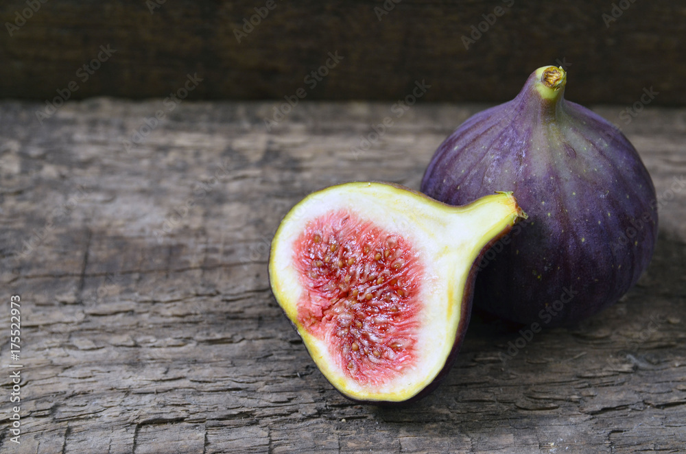 Fresh ripe fig fruits on old wooden background.Whole and sliced figs.Selective focus. Fresh ripe fig fruits on old wooden background.Whole and sliced figs.Selective focus.