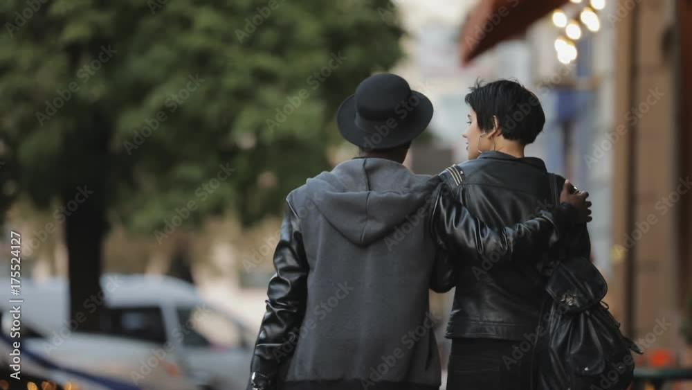 Slowmotion of white woman and black man walking together. He hugging her in city street, rear view. Slowmotion of white woman and black man walking together. He hugging her in city street, rear view.