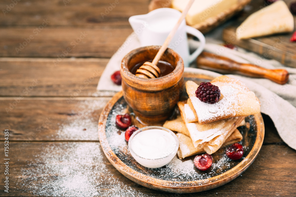 Fresh homemade crepes with honey and berries over rustic background