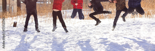 Group of cheerful children jumping in the snow in winter