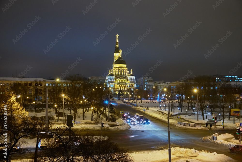 Obraz premium Night city in winter. Machines and street lights. The big cathedral is highlighted