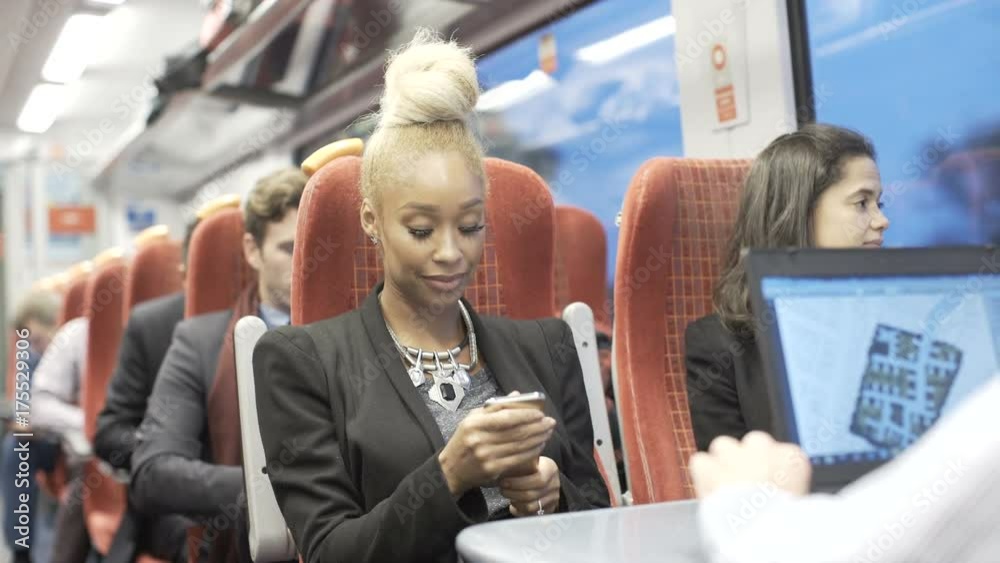  Cheerful businesswoman looking at smartphone on busy commuter train