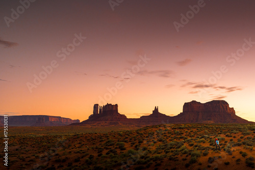 Backpacker Hiking at Monument Valley Utah USA Landscape At Dusk Under Colorful Red Tobacco Sky photo
