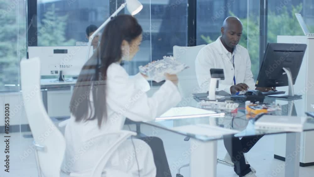 Electronics engineers working in lab, building components with 3D printer Electronics engineers working in lab, building components with 3D printer
