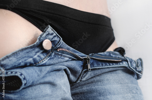 Sexy Woman Taking Off Jeans. jeans undo. Sport figure of a girl, waist, in black stings panties.
