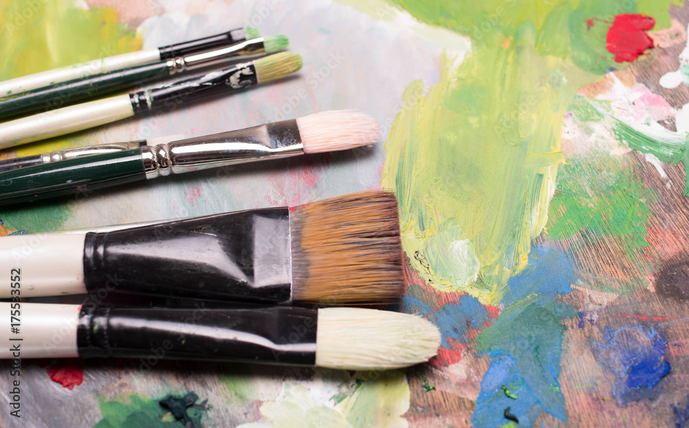 Artist paint brushes and oil paint  on wooden artistic palette background. Brush paint artistic. Tools for creative work. Back to school. Paintings Art Concept. Selective focus. Copy space. Top view.