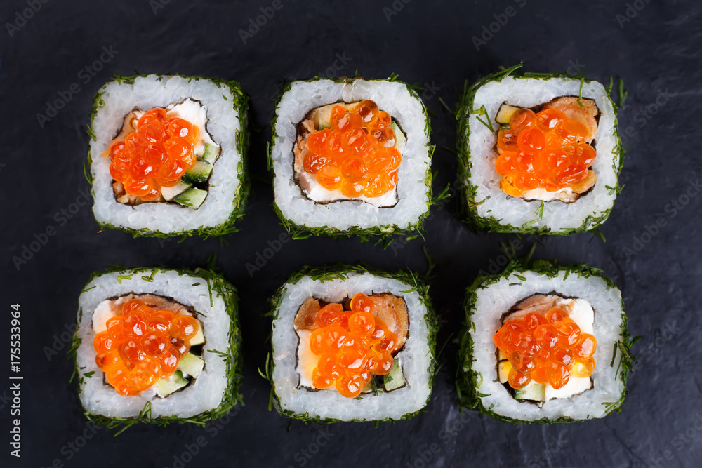 Japanese food, sushi restaurant. Delicious sushi rolls topped with caviar in chopped dill served on black slate, flat lay Japanese food, sushi restaurant. Delicious sushi rolls topped with caviar in chopped dill served on black slate, flat lay