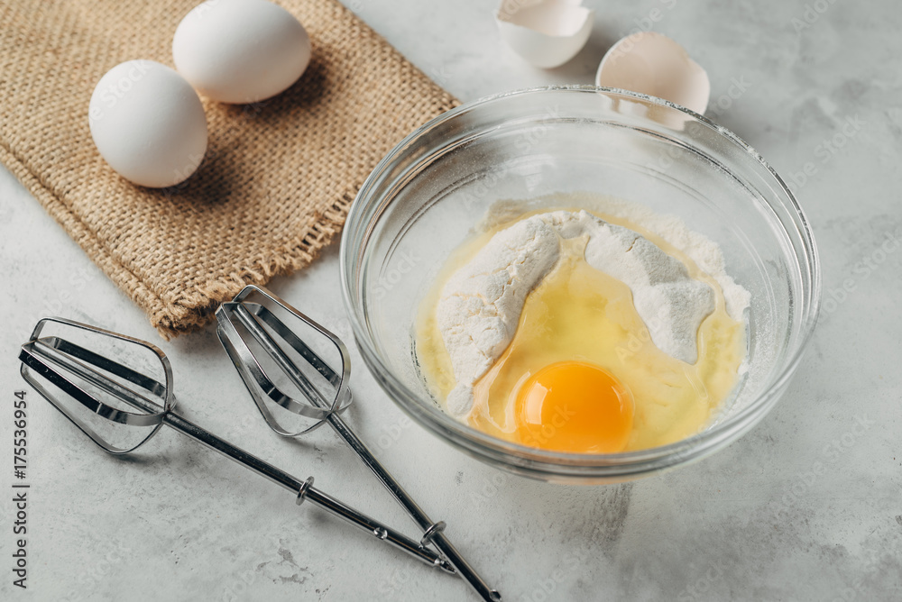 Top view photo of a broken egg on flour in a glass plate. Top view photo of a broken egg on flour in a glass plate.