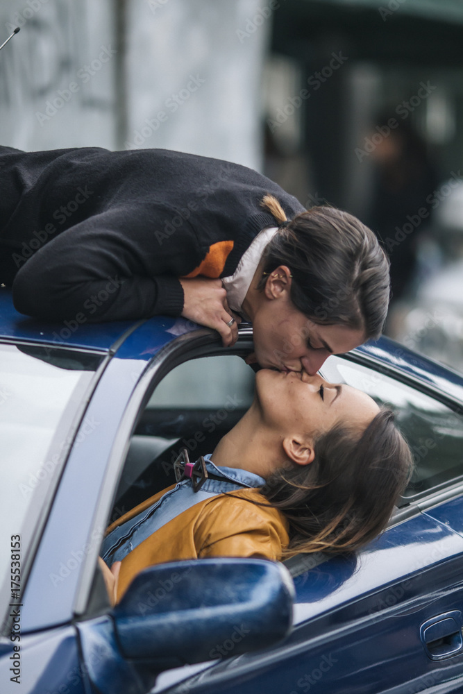 two fashionable girls in love kissing on the car roof, homosexual Stock