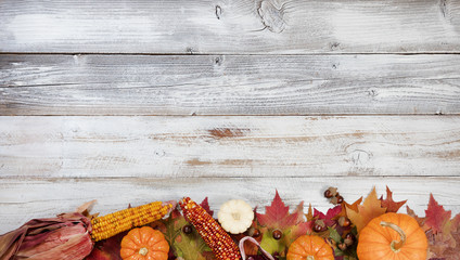 Bottom border of Autumn foliage with other fall decorations on white rustic wooden boards for thanksgiving holiday season 
