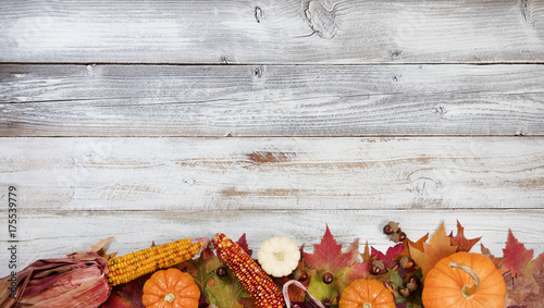 Bottom border of Autumn foliage with other fall decorations on white rustic wooden boards for thanksgiving holiday season 