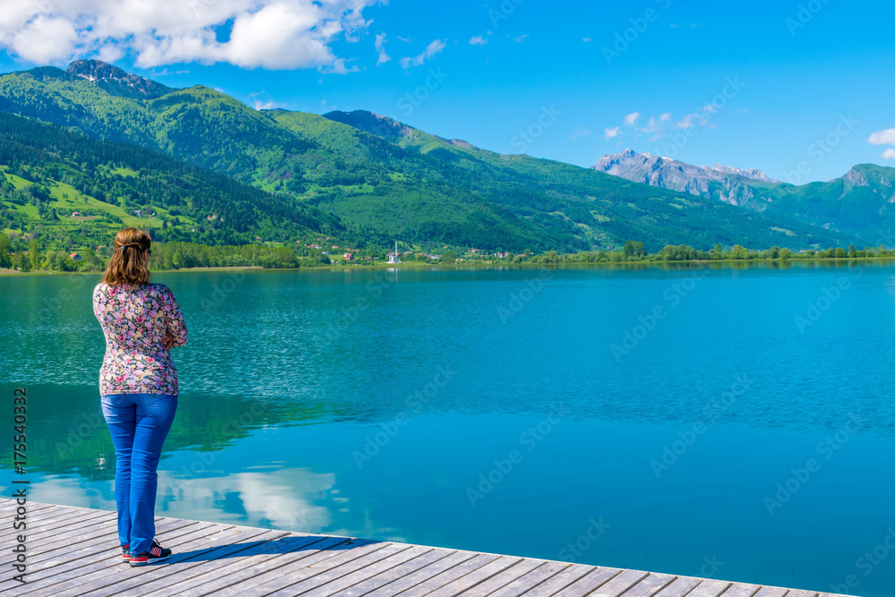 Naklejka premium A young pretty girl dreams near a mountain lake.