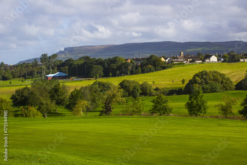 A golf fairway and green in the parkland course in the Roe river valley near Limavady in Northern Ireland with the magnificent Bienevenagh Mountain in the background photo