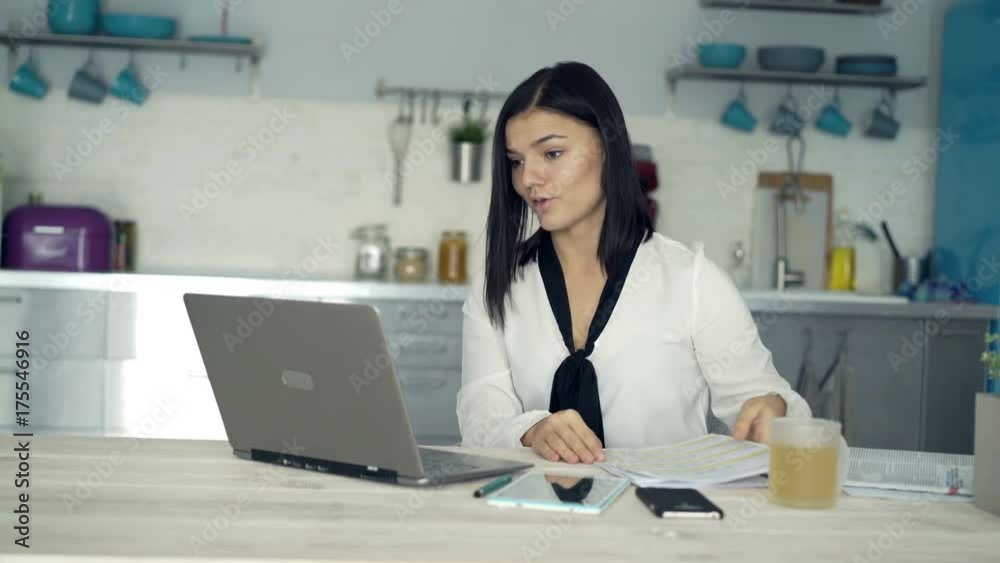 Young businesswoman with documents chatting on laptop by table at home
Young businesswoman with documents chatting on laptop by table at home