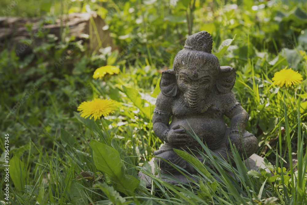ganesha stone statue in a green garden