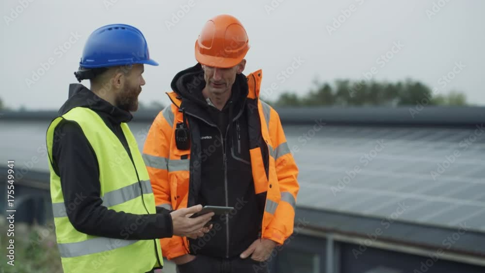 Technicians with computer tablet discussing operations at solar energy plant. Technicians with computer tablet discussing operations at solar energy plant.