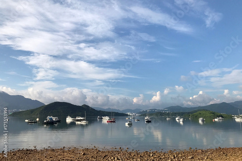 Mountain, blue sky, recreational boats and cloudscape with reflection on lake