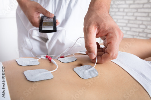 Therapist Placing Electrodes On Woman's Stomach