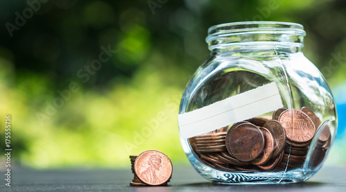 Canvas Print one cent coins in a glass jar on the table in a garden
