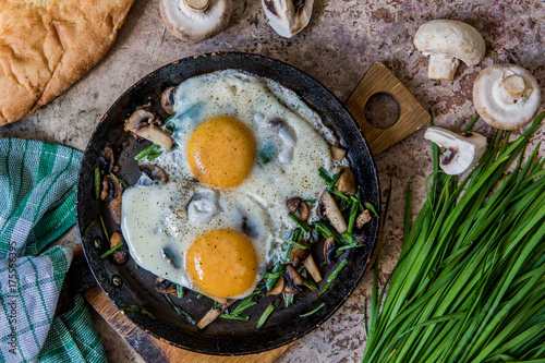 Fried eggs with mushrooms and jusai (allium ramosum). Breakfast in azian style, top view