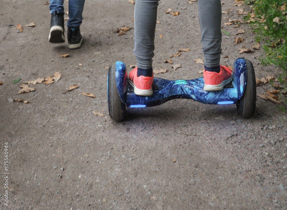 Obraz premium Gyroscooter rides on the road. The legs of a teenager on Gyroscooter goes on the road. 