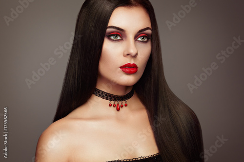 Halloween Vampire Woman portrait. Beautiful Glamour Fashion Sexy Vampire Lady with long dark Hair, beauty Make Up and Costume