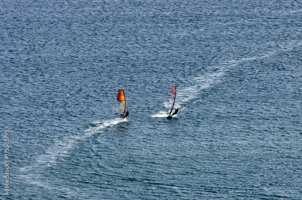 Two windsurfers on the waves of the Mediterranean sea at Cape Prasonisi, Rhodes (Greece)