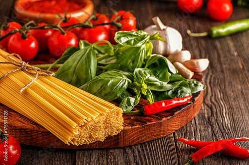 Products for cooking - pasta, tomatoes, garlic, pepper, and basil.
