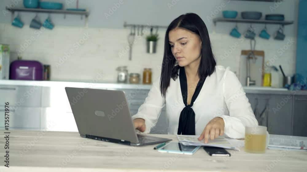 Young businesswoman working with laptop and documents by table at home
Young businesswoman working with laptop and documents by table at home