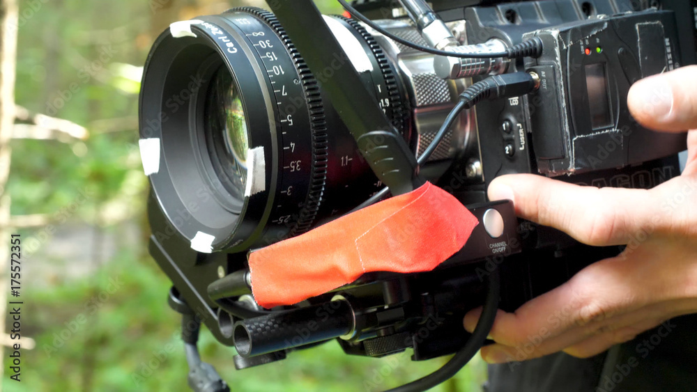 Obraz premium Man holding a camera filming a movie in the forest. Expensive camera for movie in the woods