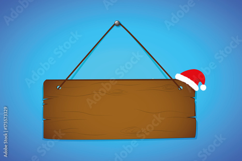 holzschild mit weihnachtsmütze auf blauem hintergrund