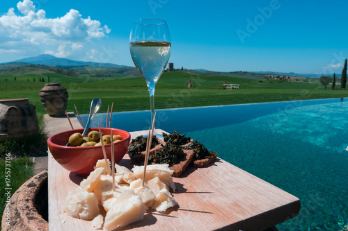 Spring aperitif in Tuscany / Closeup view of a traditional apetizer serving dish on a magnificent swimming pool in the Tuscan countryside