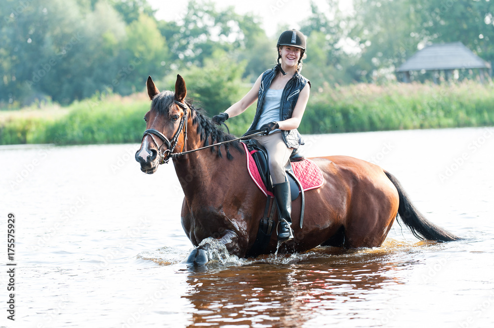 Smililng young teenage girl riding horseback in river Smililng young teenage girl riding horseback in river