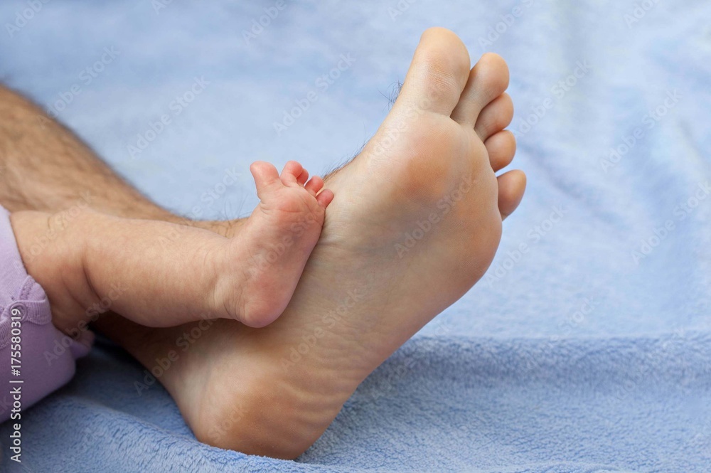 Closeup of huge foot of father and little newborn baby. Closeup of huge foot of father and little newborn baby.