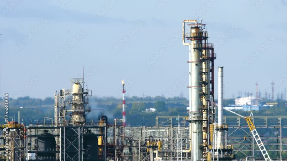 Long shot of oil refinery units in sunny weather with clouds in background. Gas industry background. Long shot of oil refinery units in sunny weather with clouds in background. Gas industry background.