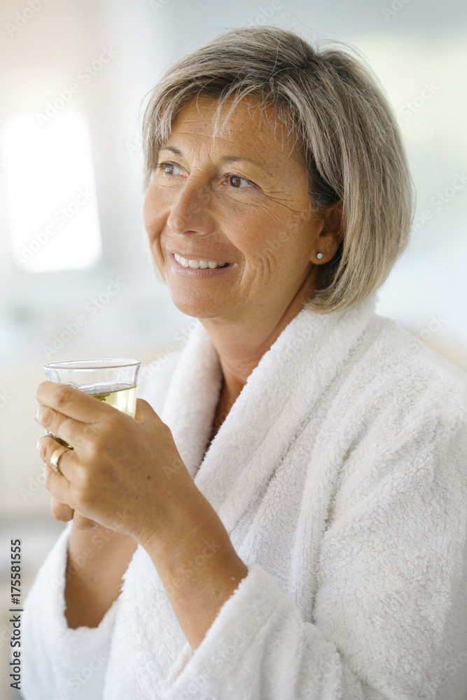 Senior woman in bathrobe drinking hot green tea Senior woman in bathrobe drinking hot green tea