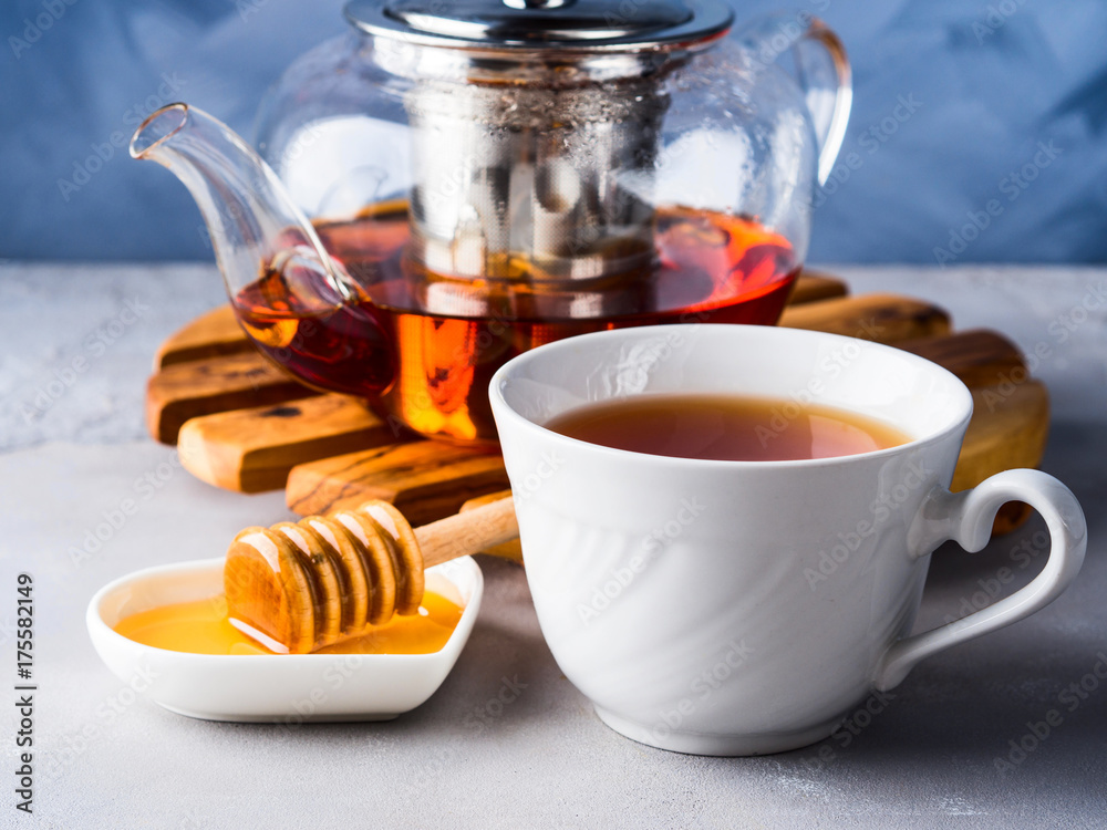 Cup of red tea rooibos and honey with glass teapot on blue Cup of red tea rooibos and honey with glass teapot on blue