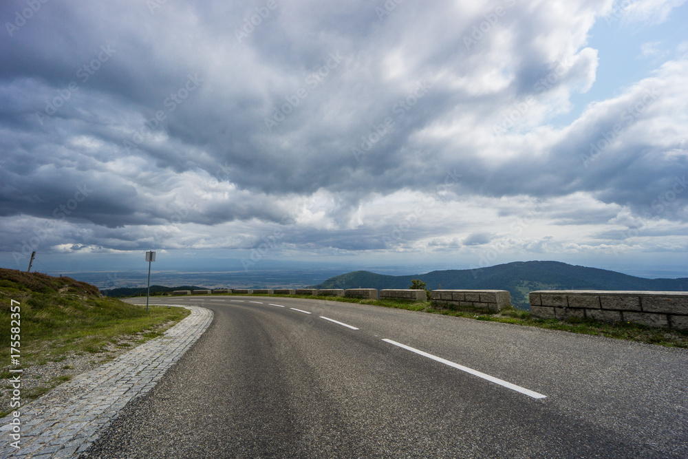 France - Left turn street of route de cretes with wide flat and mountain landscape behind France - Left turn street of route de cretes with wide flat and mountain landscape behind