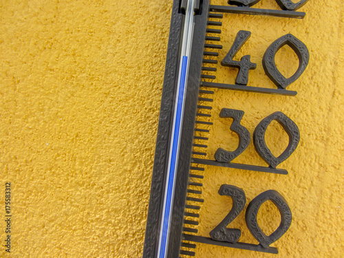 thermometer in yellow wall measuring external air temperature over forty celsius degrees photo