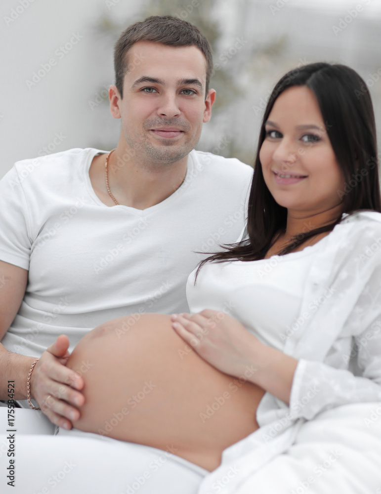 portrait of pregnant woman with husband sitting on the couch